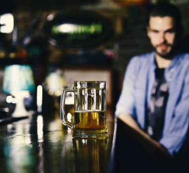 Hizmet anlayışı. Adam, tezgahın bira ile yerleştirilir. Bulanık bar arka plan fıçı birayla bardak.