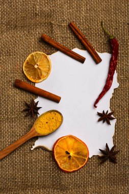 Tarçın, kurutulmuş portakal ve biber, anasonu boş kağıt, tarifi, kopya alanı çevresinde. Baharat kaşıkla beyaz kağıt yatıyordu. Mutfak tarifi kavramı. Kağıt üzerinde çul arka plan