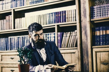 Klasik takım elbiseli adam oturur vintage iç, Kütüphane, kitap rafları arka plan üzerinde. Oldfashioned adamın yanında çay bardağı. Aristokrat gelenekleri kavramı.