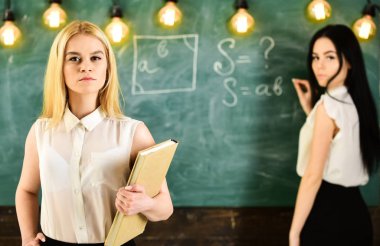 Öğrenciler ve stajyerler konsepti. Kadın tahtaya yazı yazarken kendinden emin görünüyor. Odaklanamıyor. Öğrenci, resmi giyinen öğretmen sınıfta dursun. Derse hazırlanan çekici kadınlar.