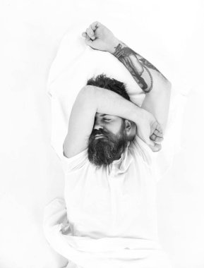 Sabah ve kavram uyan. Beyaz çarşaf yastık üzerinde uykulu yüz adamla yatıyor.