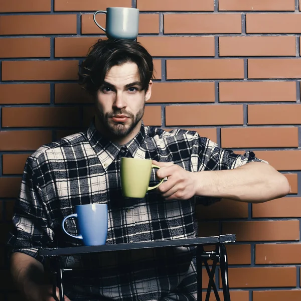 Siyah beyaz kareli tişörtlü yakışıklı adam elinde siyah tahta tepsiler, duvarla örülmüş fincanlar, kopyalama alanı, kopyalama alanı olan siyah ahşap tepsi tutuyor.