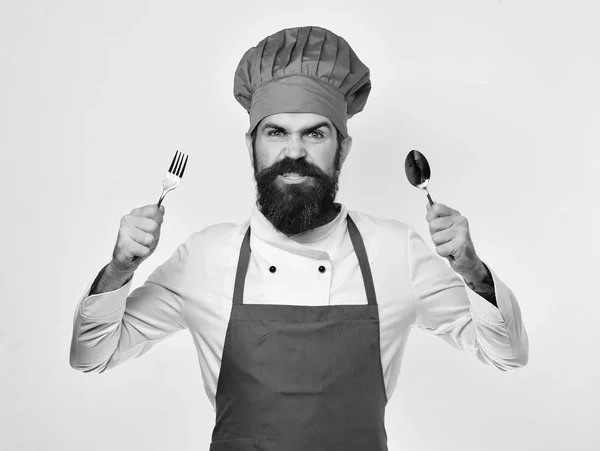 Concept d'ustensiles de restaurant. Homme avec barbe tient fourchette et cuillère sur fond blanc . — Photo