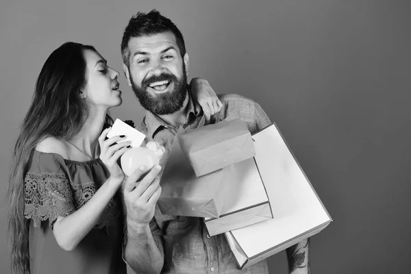 Winkelen en vrije tijd concept. Man met baard houdt credit card en piggy bank. — Stockfoto