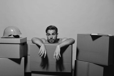 Adam kutuları, kopya alanı üzerinde eğilir. Sarı arka plan üzerinde izole sakallı adam. Kask ve klasör maço yorgun yüzü vardır.