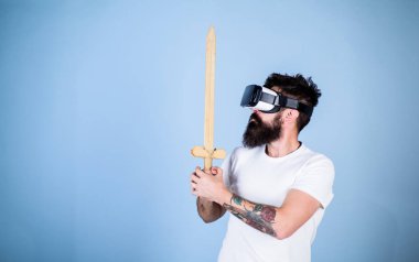 Hipster ciddi bir yüz üzerinde sanal gerçeklik oyun oyun keyfini çıkarın. Oyun kavramı. Vr gözlük, açık mavi renkli sakallı adam. Adam kafa monte ekran ile kılıç, oyun Vr oyunda mücadele tutar