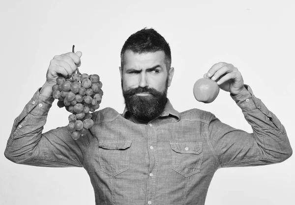 Weinbau und Herbstfrüchte Konzeptmann mit Bart hält Bündel grüner Trauben und Apfel in der Hand — Stockfoto