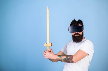 Oyun kavramı. Vr gözlük, açık mavi renkli sakallı adam. Hipster ciddi bir yüz üzerinde sanal gerçeklik oyun oyun keyfini çıkarın. Adam kafa monte ekran ile kılıç, oyun Vr oyunda mücadele tutar