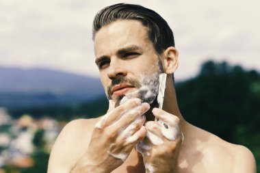 Adam ile köpük tıraş jilet ile kaplı. Seksi güçlü omuz çenesini tıraş olan bir erkek