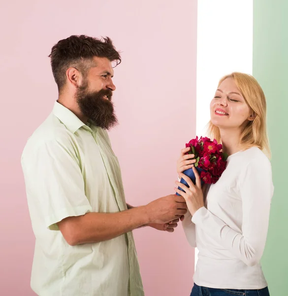 Mannen med skägg gratulerar kvinna födelsedag årsdagen holiday. Hipster skäggiga ge bukett blommor till flickvän. Par i kärlek firar semester. Par datum bukett blommor gåva. Gåva-konceptet — Stockfoto