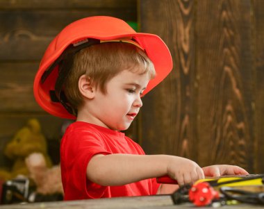 Çocuk oyun araçları ile masada. Kavram handcrafting. Kask Oluşturucu veya repairer, onarımı veya handcrafting olarak oynayan sevimli çocuk. Yürümeye başlayan çocuk meşgul yüz oyunlarında evde atölye üzerinde
