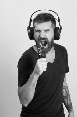 Şarkıcı sakal ve vahşi yüzü ile müzik hoşlanır. Adam, pembe arka plan söylüyor. Sakallı DJ kulaklık takıyor.