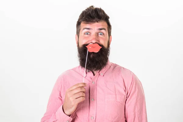 Hipster in pink shirt with stylish beard holding paper lips isolated on white background. Birthday party of handsome bearded man, celebration concept. Bearded man with surprised look raising eyebrows — Stock Photo, Image