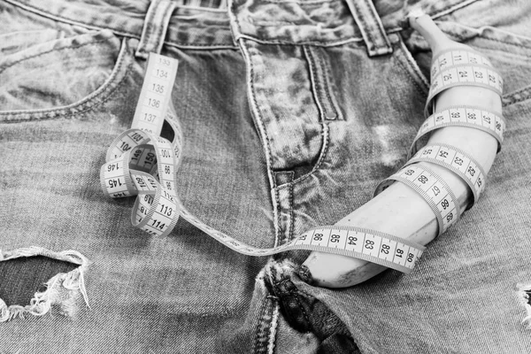 Health and male sexuality concept. Banana wrapped with blue measure tape on jeans crotch — Stock Photo, Image