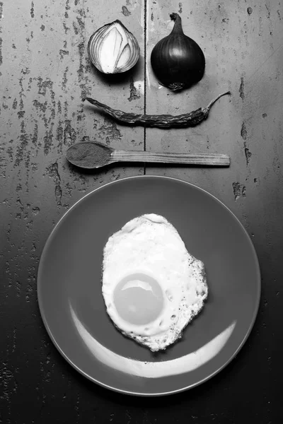 Kırmızı biber, kırmızı biber biber ve soğan surat kaşıkla yakınındaki yumurta ile çanağı. Kırmızı plaka siyah arka plan, üstten görünüm üzerinde yerleştirilen gıda