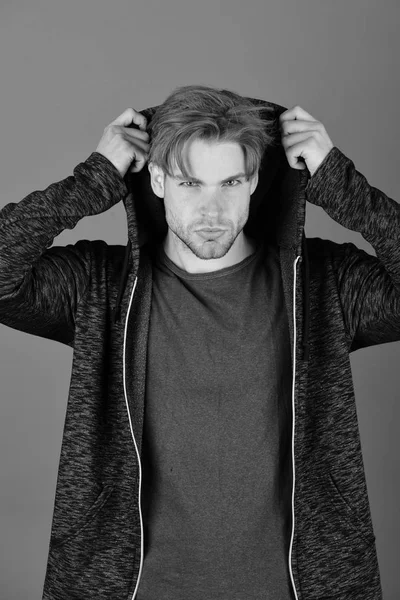 Erkeklik ve spor moda kavramı. Mor zemin üzerine sarı saçlar olan adam. Kıl koyu mavi tshirt ve gri kapşonlu adamla.