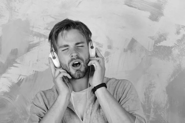 Style de vie musical. Hipster élégant aux yeux bleus avec smartphone. Américain beau barbu avec écouteurs. Européen gars avoir du plaisir . — Photo