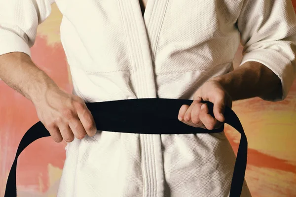 Le gars pose en kimono blanc avec ceinture noire, gros plan. Combattant de karaté avec ajustement mains fortes se prépare à se battre . — Photo