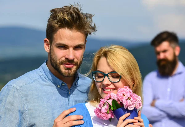 Casal apaixonado namoro enquanto homem barbudo ciumento assistindo esposa enganá-lo com amante. Conceito de infidelidade. Casal romântico namorados flores bouquet. Amantes abraços ao ar livre flertar relações românticas — Fotografia de Stock