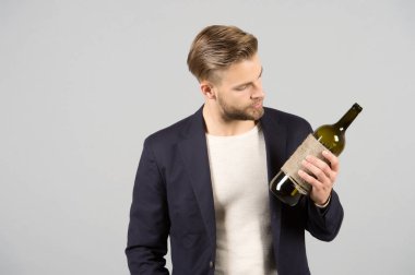 Güzel seçim. Adam şişe alkol içki tutar. Sosyal ve kültürel açıdan içme. Adam düşünceli tahmin şişe alkol. İşadamı resmi takım elbise güvenle gri arka plan ağırlıyor