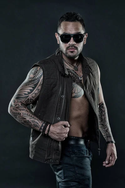 Tattoo model with beard on unshaven face. Tattooed man with six pack and ab. Bearded man with tattoo on chest and arms. Fashion style and trend. Fashion macho in trendy sunglasses, vintage filter