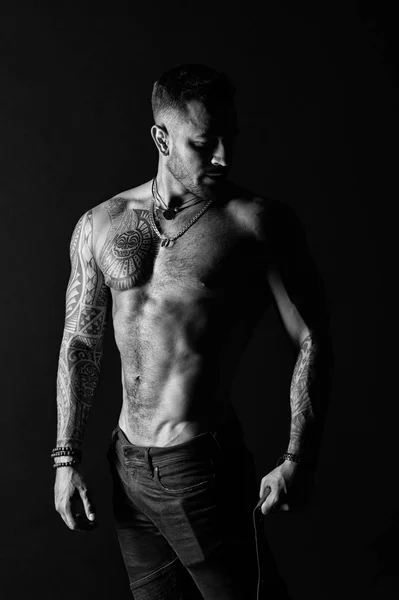 Homem com braço tatuado e peito. Homem barbudo com torso forte. Modelo de tatuagem com barriga sexy. Desportista ou atleta de jeans de moda. Cuidado com o corpo com fitness e esporte, preto e branco — Fotografia de Stock