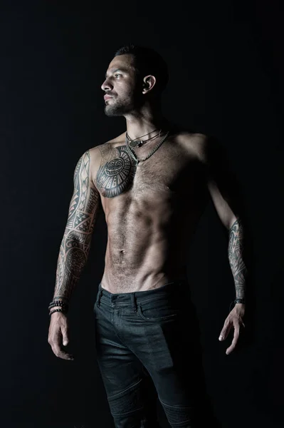 Tatuato uomo mostra torso muscolare sexy. Sportsman con sei pack e ab. Culturista con bicipiti e tricipiti. Modella con tatuaggio in jeans. Cura del corpo con fitness e sport in filtro vintage — Foto Stock