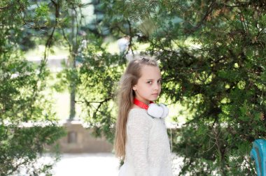 Yaz parkta uzun sarı saçlı çocuk. Küçük kız oyun temiz hava açık. Doğa kulaklıktan olan moda çocuk. Tatil yaz ve rahatla. Müzik ve modern teknoloji