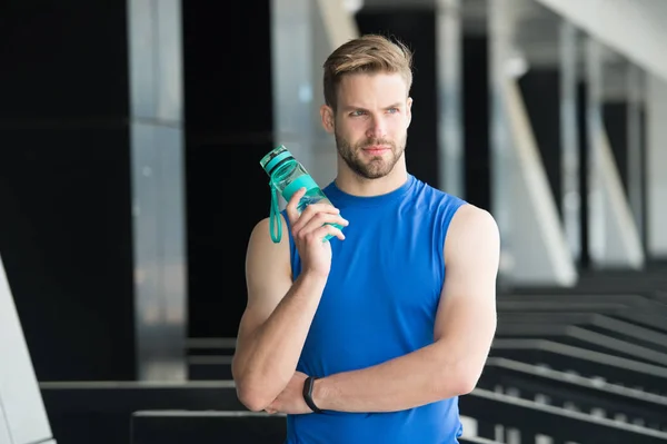 Sed y salud. El deportista tiene una botella de agua en el estadio. Ajuste hombre con frasco de plástico al aire libre. Mantente hidratado y saludable. El agua es parte de un entrenamiento saludable. Deporte y fitness — Foto de Stock