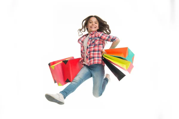 白に隔離されたショッピングバッグで幸せな女の子ジャンプします。紙袋で少しお店の笑顔。子供の買い物ファッション。買い物と販売。誕生日の準備。ブラック・フライデー。動きの楽しさ — ストック写真