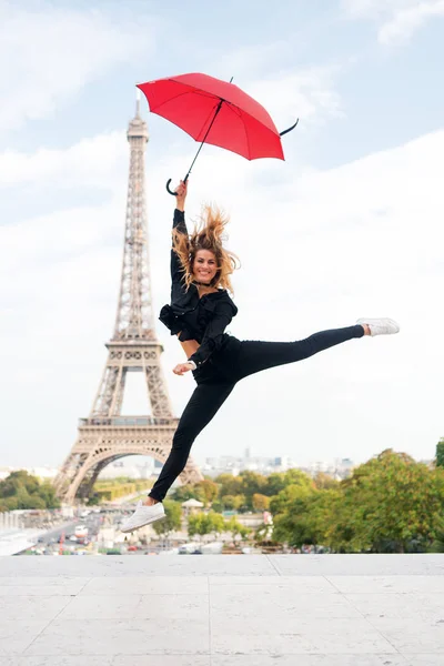 Senhora com guarda-chuva animado sobre visitar Torre Eiffel, fundo do céu. Os sonhos tornam-se verdadeiros. Senhora turista desportiva e ativa no centro da cidade de Paris salta. Menina turista desfrutar de caminhada e passeios — Fotografia de Stock