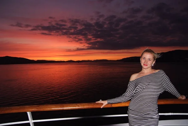 Mujer sonrisa en la cubierta del barco en el cielo dramático sobre el mar en Bergen, Noruega. Mujer feliz disfrutar de los viajes por mar en la noche. Puesta o salida del sol. Vacaciones de verano en el mar. Viaja por el agua. Aventura y vagabundeo — Foto de Stock