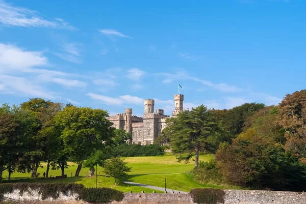 Lews Castle on estate landscape in Stornoway, United Kingdom. Castle with green grounds on blue sky. Victorian style architecture and design. Landmark and attraction. Summer vacation and wanderlust