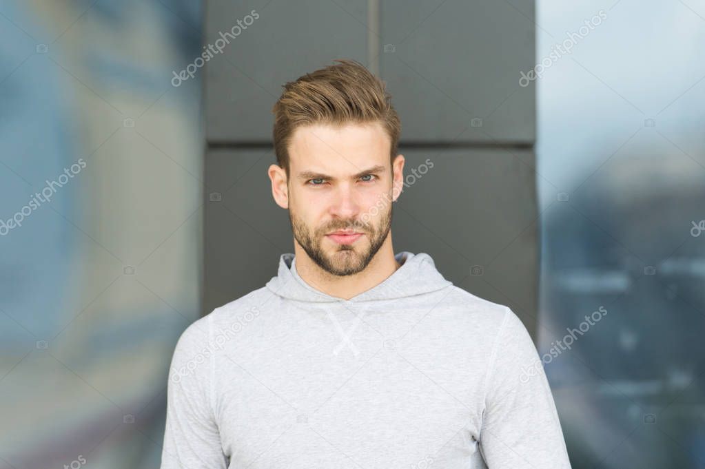 Casual in style. Man with beard on serious face outdoor. Macho in grey sweatshirt on fresh air. Taking a minute break. Sporty handsome