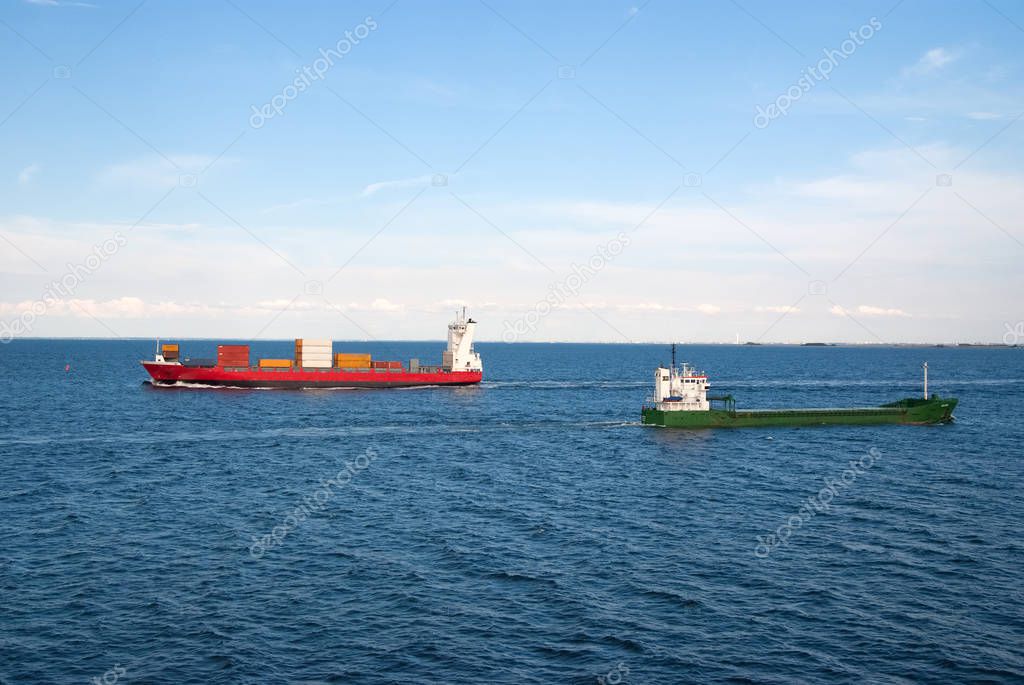 Barges ship cargo containers in sea in Copenhagen, Denmark. Cargo ships float in blue sea on idyllic sky. Marine transport and transportation. Shipping and shipment. Logistics