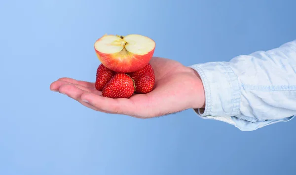 Frische biologische Ernte reifer Obstbeeren. Hand Erdbeere und Apfelfrucht passen perfekt zu frischem Saft. Saftzutaten. männliche Hand mit Erdbeeren und der Hälfte des apfelblauen Hintergrundes — Stockfoto