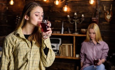 Arkadaşlar sıcak bir atmosferde, ahşap iç mulled şarap tadını çıkarın. Rahatlatıcı ve mulled şarap içme kızlar. Dinlenmek ve rahatlamak kavramı. Rahatlatıcı, defocused kareli giysiler rahat yüzleri üzerinde arkadaşlar