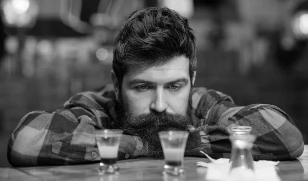 Guy wasting time in bar, defocused background. Depressed and sad man sit alone in bar or pub