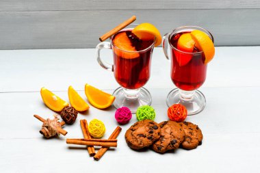 Portakal dilim yakınındaki mulled şarap. İçki ya da portakal ve tarçın ile içecek. Alkollü kokteyl kavramı. Gözlük mulled şarap veya portakal dilimleri ve çerezleri beyaz arka plan üzerinde yakın sıcak elma şarabı ile