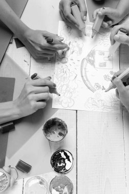 Sanatçı ahşap masa boyalar ve renkli kağıt ile. İşaretleri erkek ve kadın elinde beyaz kağıt üzerine çizmek