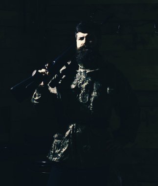 Av hayvanı bekçisi konsepti. Avcı, acımasız hippi, sert suratlı, silahlı ve avlanmaya hazır. Sakallı bir adam kamuflaj kıyafeti giyiyor. Omzunda tüfek taşıyor.