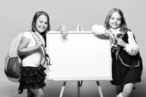 Школярки поруч з дошкою маркерів на синьому фоні — стокове фото