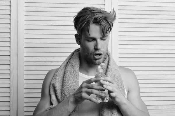 Athlete with strong muscles after shower. Man with bottle of water and green towel — Stock Photo, Image