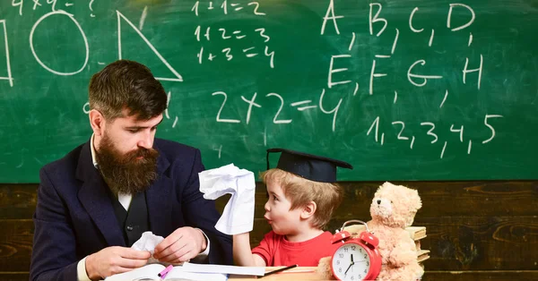 個々 の教育コンセプトです。教室でのレッスン。若い先生は、机に座っている小さな子供。彼の紙のおもちゃを見せて興奮した少年 — ストック写真