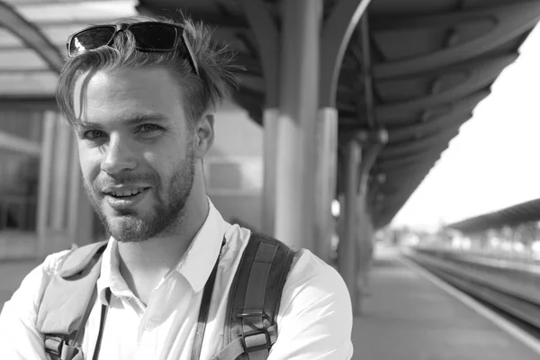 Missed train and travelling concept. Tourist with smiling face and backpack. Young man on platform