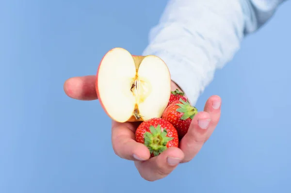 자신을 도울. 손으로 받아 딸기와 사과 과일을 제안합니다. 과일 유기농 치료 또는 간식입니다. 잘 익은 과일의 신선한 추수입니다. 딸기와 애플 파란색 배경의 절반 남자 손 — 스톡 사진