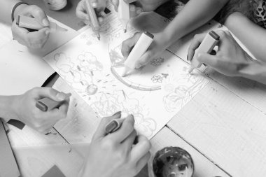 Sanat ve fikir kavramı. Sanatçı ahşap masa boyalar ve renkli kağıt ile. İşaretleri erkek ve kadın elinde beyaz kağıt üzerine çizmek