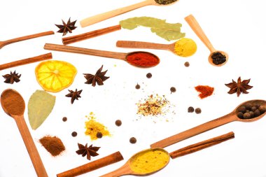 Kaşık mutfak otlar ve baharatlar ile dolu. Kaşık mutfak otlar, Yıldız anason ve beyaz zemin üzerine defne yaprağı ile. Baharat ve kuru malzemeyi kaşıklarla bileşimi. Mutfak sanat kavramı