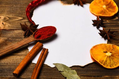 Baharatlar, beyaz kağıt mutfak otlar yatıyordu. Mutfak tarifi kavramı. Tarçın, kurutulmuş portakal ve biber, Yıldız anason lay boş kağıt, tarifi, çevresinde yer kopyalayın. Kağıt ahşap arka plan üzerinde