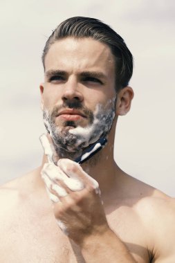 Açık gökyüzü arka plan üzerinde kıl olan adam. Maço konsantre yüz tıraş ile çene ustura ile